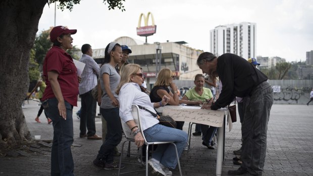 Opposition supporters sign petitions for the removal of Supreme Court justices in Caracas, Venezuela, on Tuesday.
