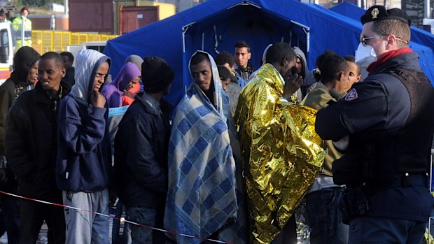 Rescued migrants line up after disembarking from an Italian Coast Guard ship in the harbour of Palermo, Sicily, southern Italy.