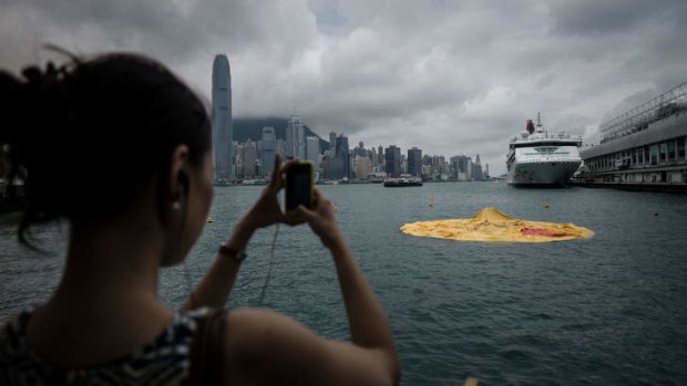 Let down: a woman takes a picture of the duck as it lies deflated.
