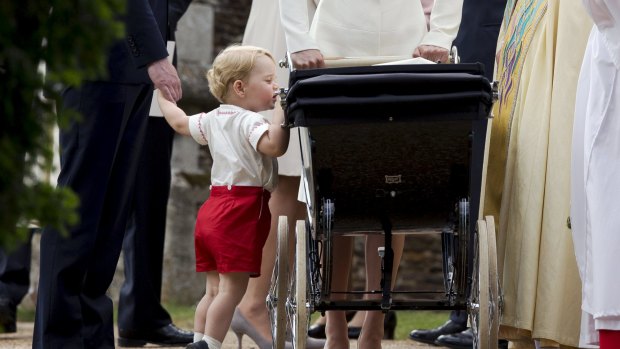 Prince George looks into the pram of his sister Princess Charlotte.