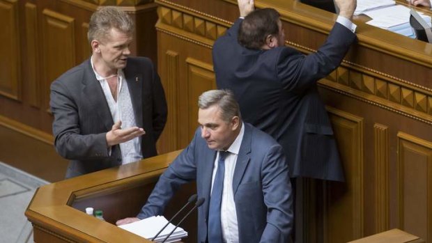 Anatoly Myarkovsky, first deputy finance minister, delivers a speech while opposition deputies react next to speaker's rostrum during a session of the parliament in Kiev June 18, 2013.