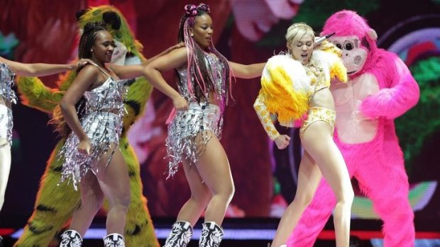 Conga line of sorts: Miley Cyrus leads her dancers and a pink guerrilla during her Sydney show.