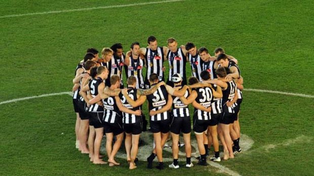 Collingwood players gather in the centre of the MCG after their triumph.