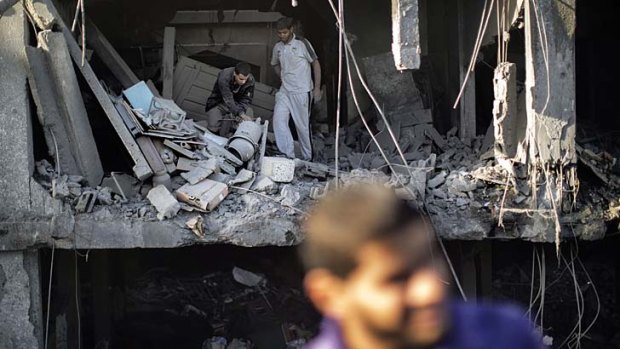 Palestinians inspect their damaged house following Israeli air strike.