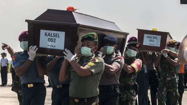 Indonesian police and military personnel carry coffins with the remains of a passengers of the AirAsia flight 8501 in Surabaya, eastern Java island.