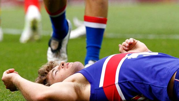 Bulldogs midfielder Callan Ward lies on the ground after an incident with Suns defender Campbell Brown.