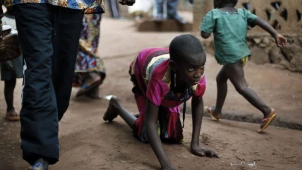 Polio-stricken Hamamatou Harouna crawls to the restroom on the grounds of the Catholic Church where she and hundreds of others have found refuge.