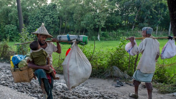 A Rohingya Muslim tries to balance his son as he carries his belongings near Balukhali refugee camp, Bangladesh.