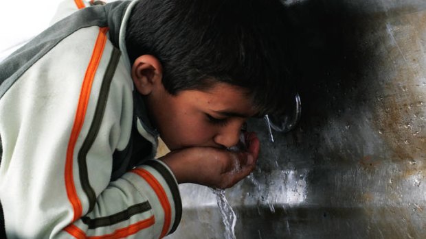 Palestinian children fill bottles with water from a public tap in Khan Younis in Gaza.