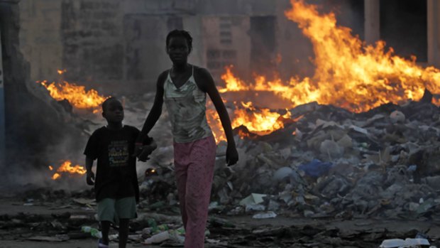 Survivors of Haiti's earthquake walk along a dump near the centre of Port-au-Prince.