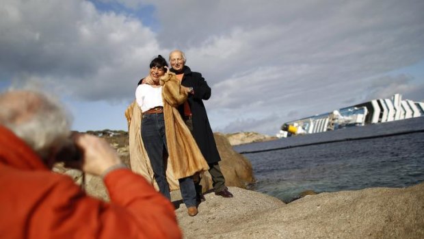 Tourists pose in front of the stricken Costa Concordia.