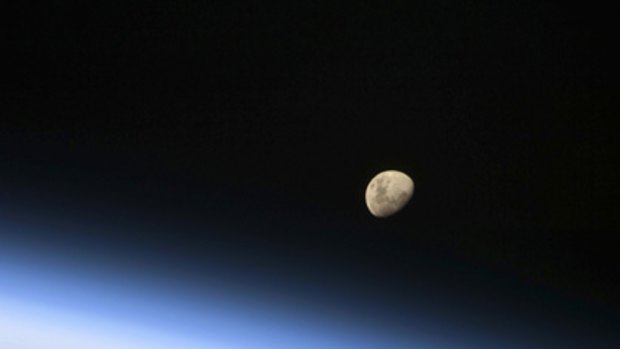 The final frontier ... (top) a gibbous moon is visible above Earth's atmosphere, in this NASA handout photo taken on August 30, 2009 and (bottom) European Space Agency astronaut Christer Fuglesang works outside the International Space Station on Saturday, September 5.