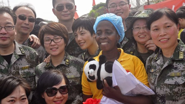 Ebola patient Beatrice Yardolo, centre, surrounded by Chinese military health workers as she leaves the Chinese Ebola treatment centre in Monrovia on Thursday.