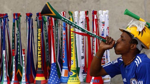 A street vendor blows a vuvuzela as he tries to attract customers.