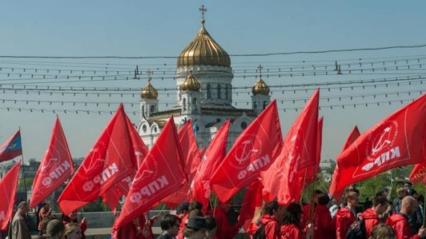 Russian Communist Party activists carry red flags and banners in front of the Christ the Saviour cathedral in central Moscow during their traditional May Day rally.