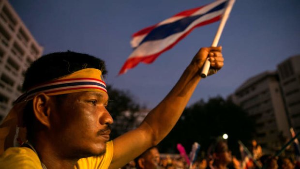 A man holds up a flag and listens to speeches as anti-government protesters occupy the Thai Finance ministry for a third day.