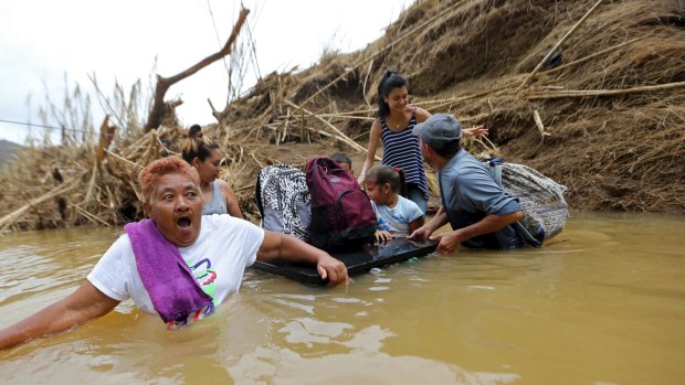 Marta Sostre Vazquez wade into the San Lorenzo Morovis River with her family after their home was destroyed.
