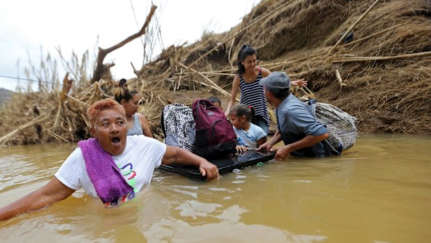 Marta Sostre Vazquez wade into the San Lorenzo Morovis River with her family after their home was destroyed.