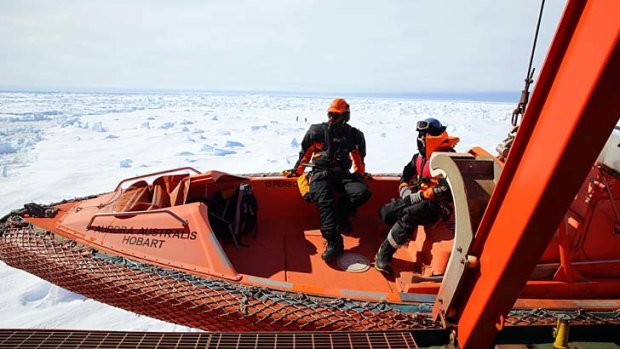 Rescuers aboard the Australian icebreaker Aurora Australis are lowered on a rescue boat to an ice floe next to the ship where a Chinese helicopter will land with passengers from the Akademik Shokalskiy.