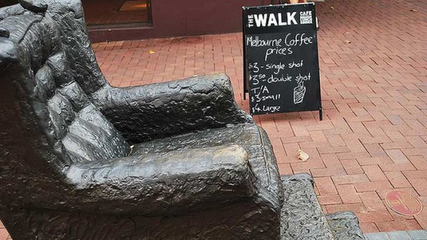 A view of The Walk Cafe's sign, advertising coffee at "Melbourne prices", from the sidewalk.