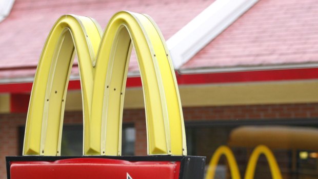 A man has been charged after allegedly spitting in the face of a young McDonald's drive-through worker.