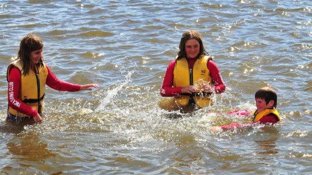 From left: Sophie Walston, Eliane Delarue and Tom Daniels from the YMCA sailing club splash in Lake Burley Griffin on Friday as Canberra reached a top of 41.6 degrees.