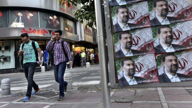 Two Iranian men walk past posters of presidential candidate Mohsen Rezaei, a former Revolutionary Guard commander, a day prior to the election, in Tehran, Iran, Thursday, June 13, 2013.