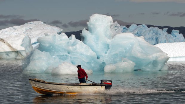 A fisherman sails past melting icebergs in Narsaq, Greenland.