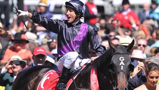 A triumphant Damien Oliver rides his third Melbourne Cup winner, Fiorente, past the cheering crowd at Flemington.