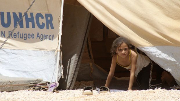 A refugee girl looks out from a tent at a refugee camp in Mafraq.