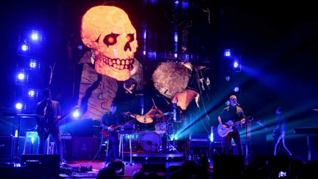 Queens of the Stone Age on-stage in LA with illustrator Boneface's menacing animations in the background.