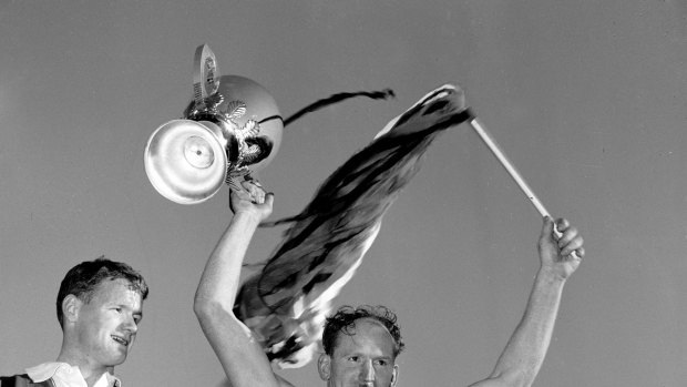 Still the one: Darrel Baldock holds the premiership cup aloft in 1966 after trading jumpers. He is alongside Collingwood captain Des Tuddenham.