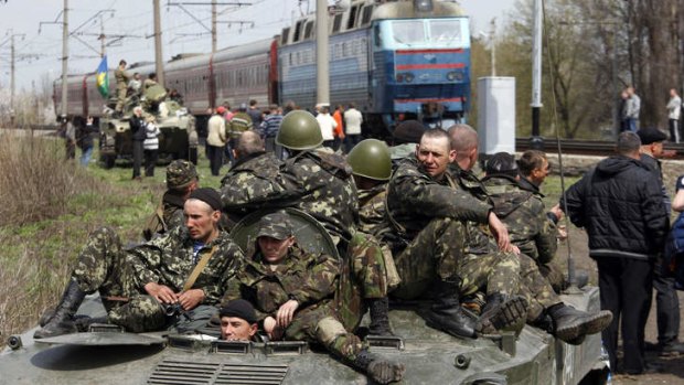Pro-Russian activists block Ukrainian men riding on armoured combat vehicles.