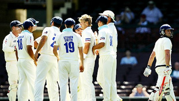 NSW teammates congratulate captain Shane Watson (without a cap) after taking the wicket of Michael Hill on the opening day of the Shield clash against Victoria at the SCG.