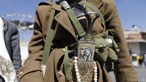 A Houthi fighter wears a traditional dagger (Jambiya) with a picture of a slain comrade on it as he poses for a photo outside a presidential guards barrack on a mountain overlooking the presidential palace in Sanaa.