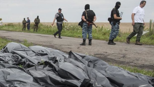 Pro-Russian fighters walk on a road with victims' bodies lying in bags by the side at the crash site of a Malaysia Airlines jet near the village of Hrabove in eastern Ukraine on Saturday.