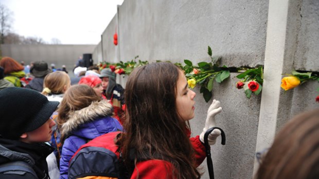 Flowers are placed in a preserved segment of the Berlin Wall at a commemoration to mark its fall 20 years ago.