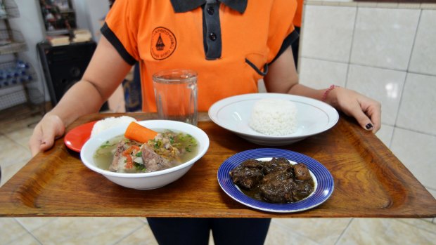 A waiter serves soup and "Sangsang", a traditional cuisine of North Sumatra in Indonesia, which is made from the meat and blood of dog with chilli, in East Jakarta, Indonesia, in 2015.