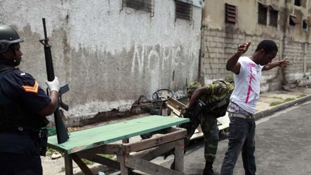 Military checkpoint ... a man is frisked   in the pockmarked Tivoli Gardens district of Kingston,  a scene of  recent violence.