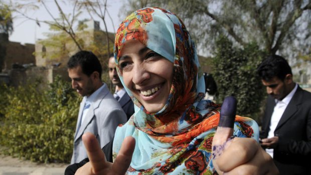 The Arab world's first female Nobel peace laureate, Tawakkul Karman, flashes the V for "victory sign and shows her ink-stained thumb after casting her vote outside a polling station in Sanaa on February 21.