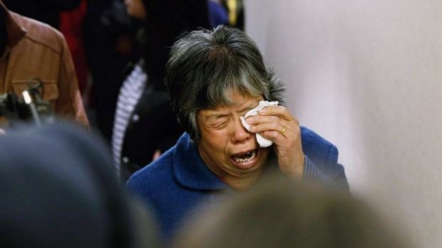 A family member of a passenger from the missing Malaysia Airlines flight MH370 reacts after the announcement.