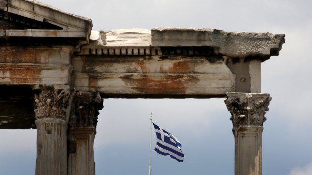 The Greek flag is framed by the arch of Hadrian atop the Acropolis hill in Athens.