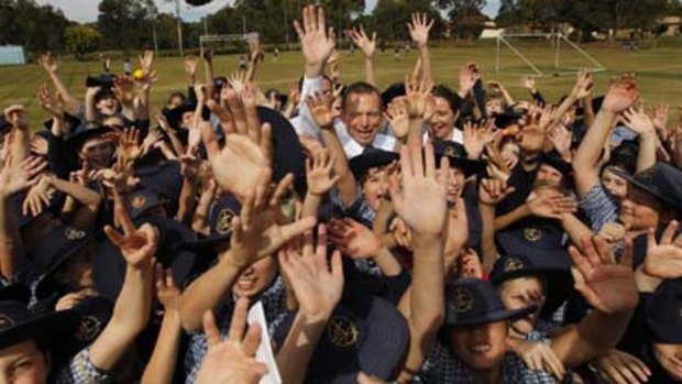 Opposition Leader Tony Abbott on the school oval with students during a visit to the Faith Lutheran College in Redlands in the south-east Queensland seat of Bowman today.