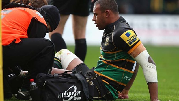 Courtney Lawes of Northampton receives attention to an injury to his left leg.