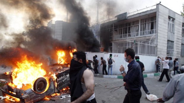 Protesters burn a car and attack a building in Iran.