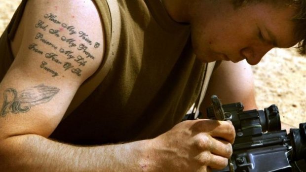 US soldier Roy Lawrence, of Maine, cleaning his weapon somewhere in Iraq in March 2003. The wars in Afghanistan and Iraq saw rules on tattoos loosened, but they have since been revisited.