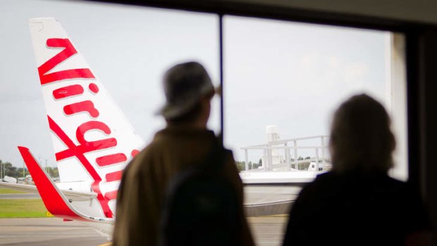 Passengers walk past a Virgin Boeing 737 aircraft.