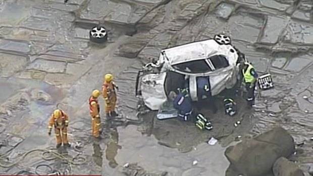 Rescue workers at the crash site near Apollo Bay work to free a woman trapped in her car at the base of the cliff.