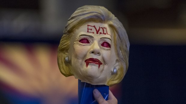 Keeping it classy - and factual: a Trump fan holds a mask of Hillary Clinton.