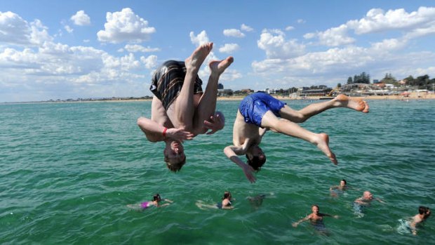 Eighteen-year-olds Andrew Burnham from Rowville and Nathan Spikin of Ferntree Gully perform backflips off the pier at the beach in Frankston.